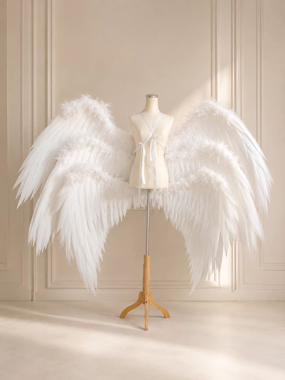 Soft white medium span angel cosplay wings on a dress form.