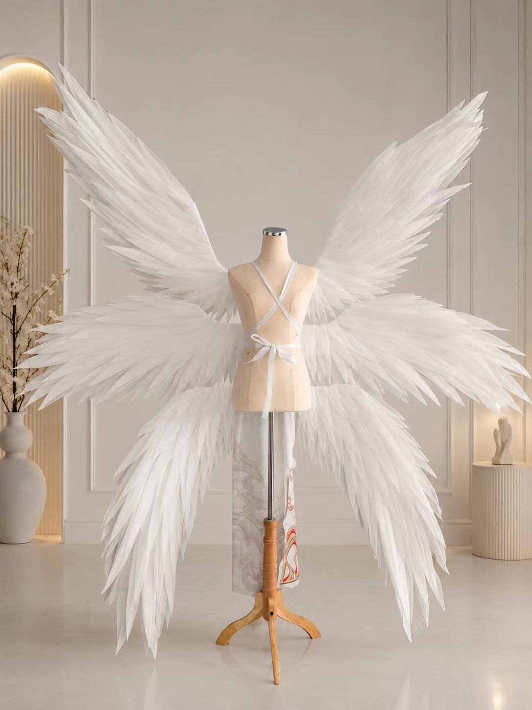 Layered long white feather angel cosplay wings displayed on a dress form.