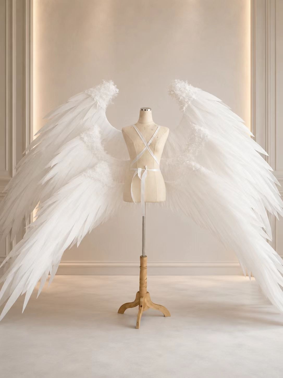 Wide white custom angel wings photographed on a dress form.