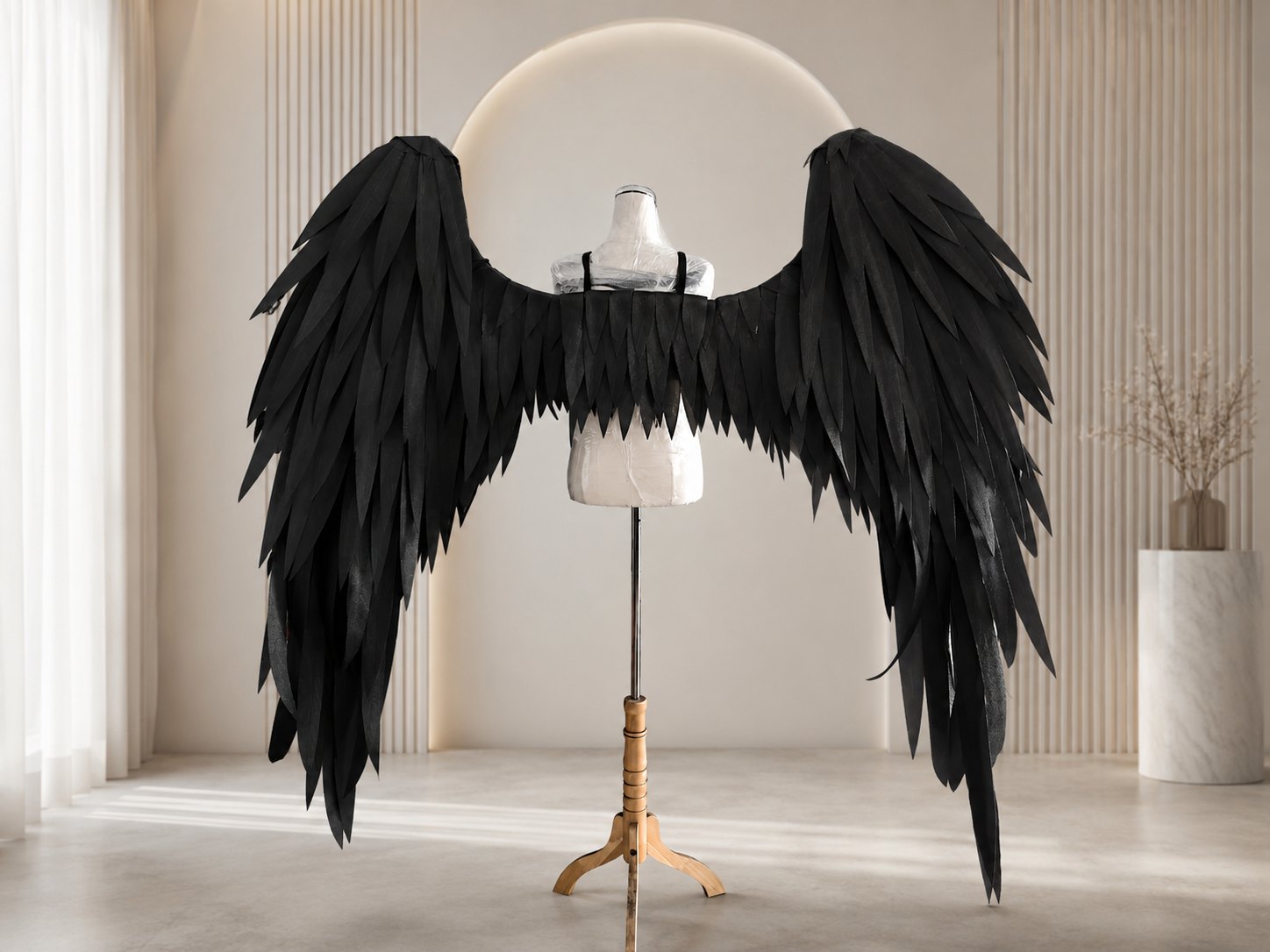 Full width black feather cosplay wings on a dress form.
