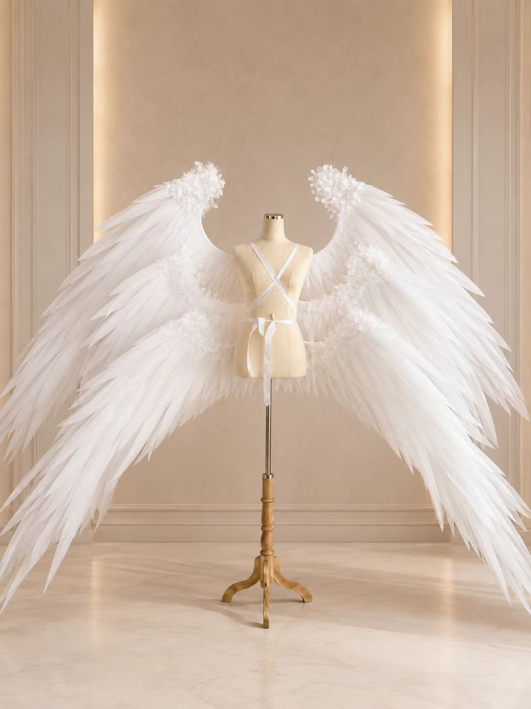 Large white angel cosplay wings with harness straps on a dress form.