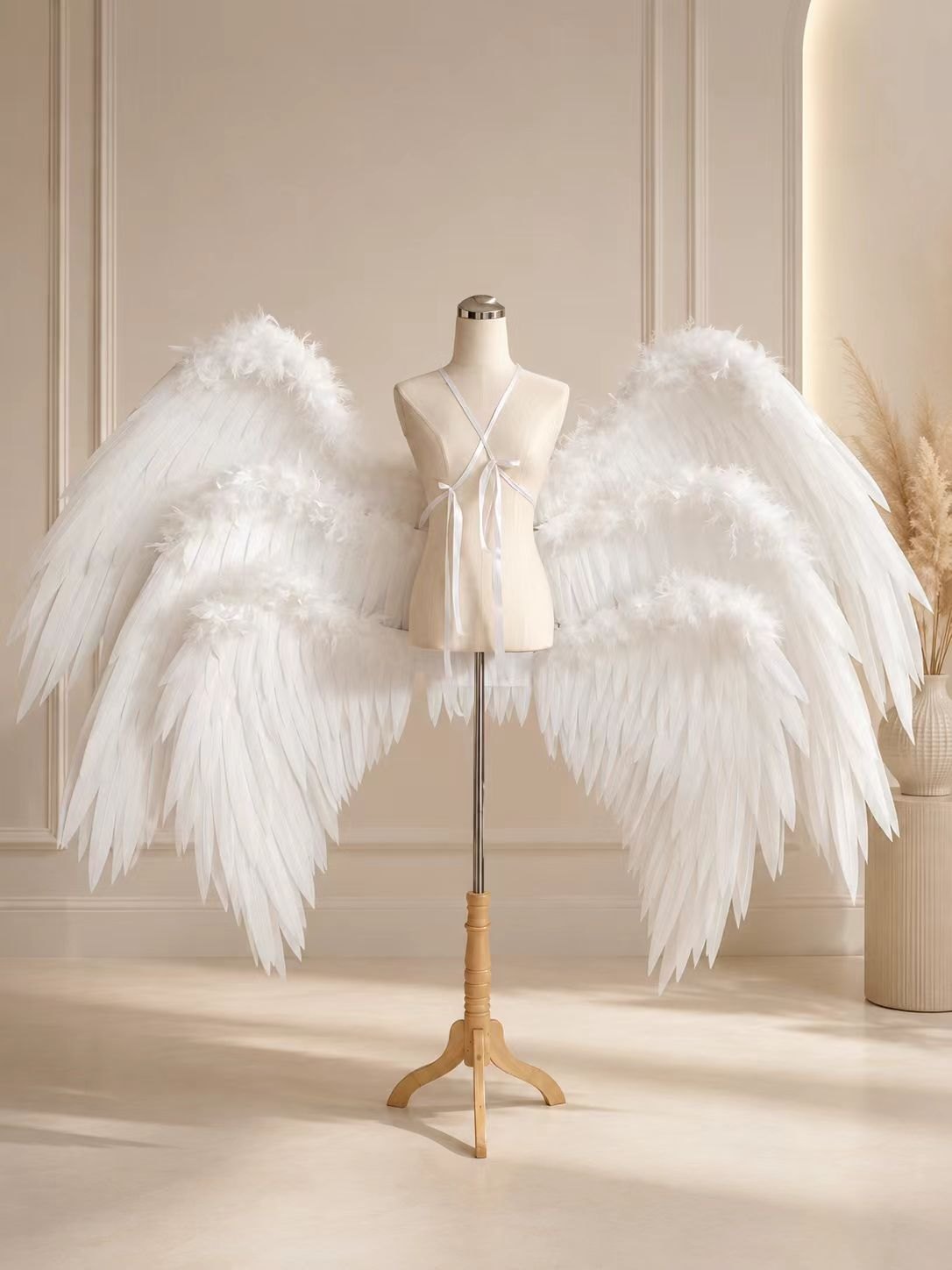 Rounded white custom cosplay angel wings with dense feather volume on a dress form.