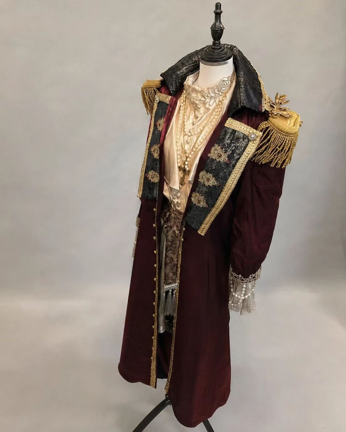 Arthur Kirkland Hetalia pirate cosplay costume with burgundy and black ornate coat, gold-stamped brocade collar, ruffled shirt, decorated pirate hat, and gold ceremonial epaulettes.