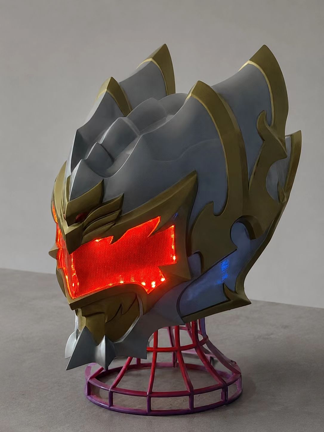 Handheld custom cosplay helmet with gold and red painted finish.