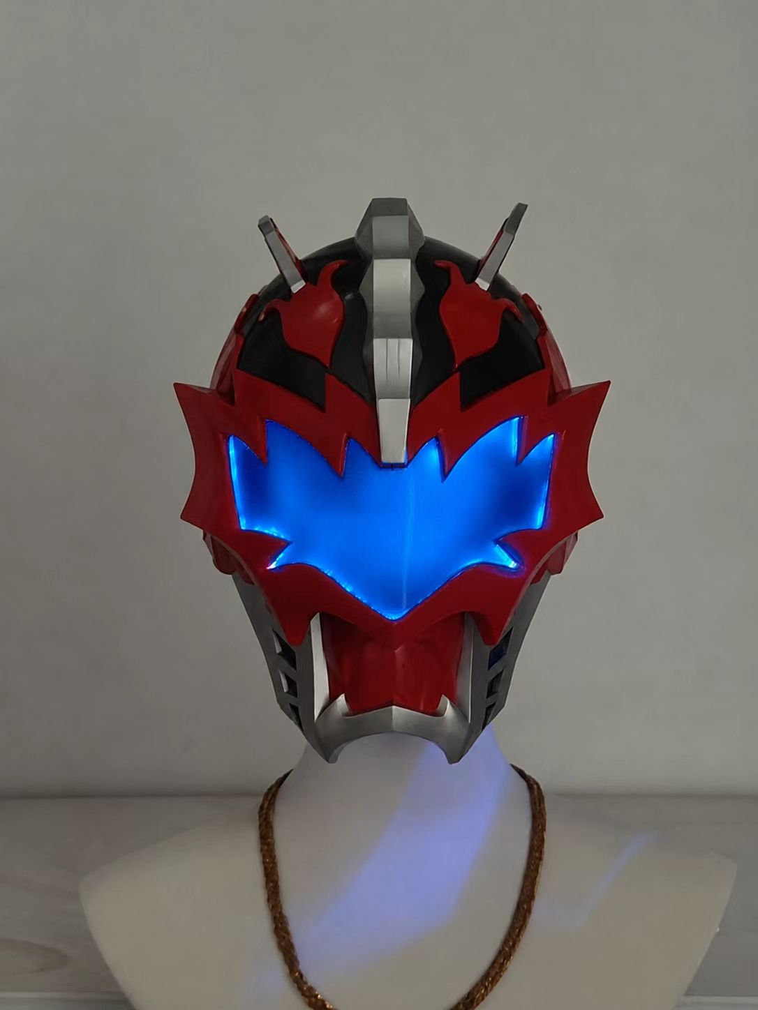 Silver and gold custom cosplay helmet displayed on a stand.