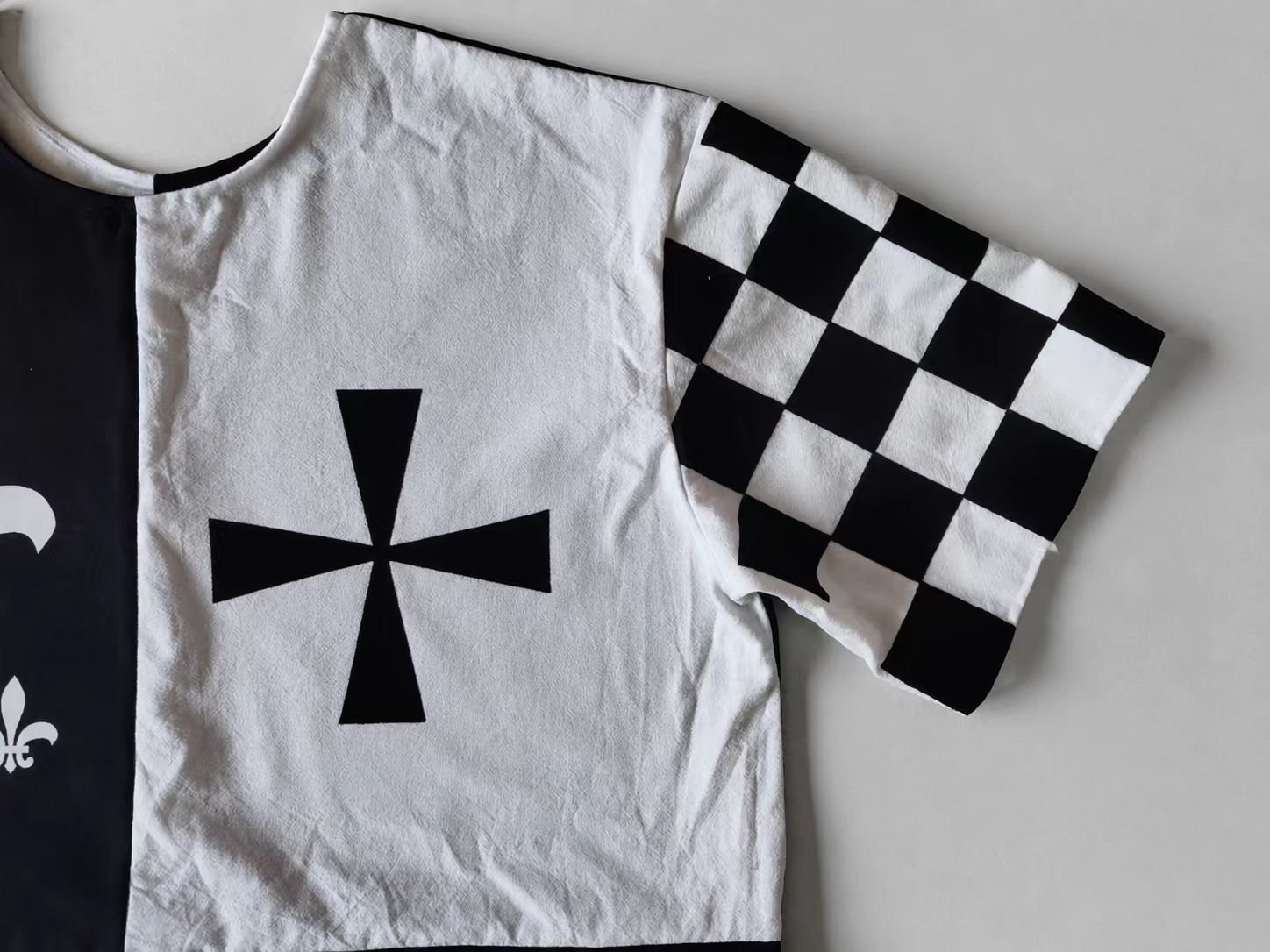 Black and white medieval cosplay tabard with cross motif and checker sleeve.