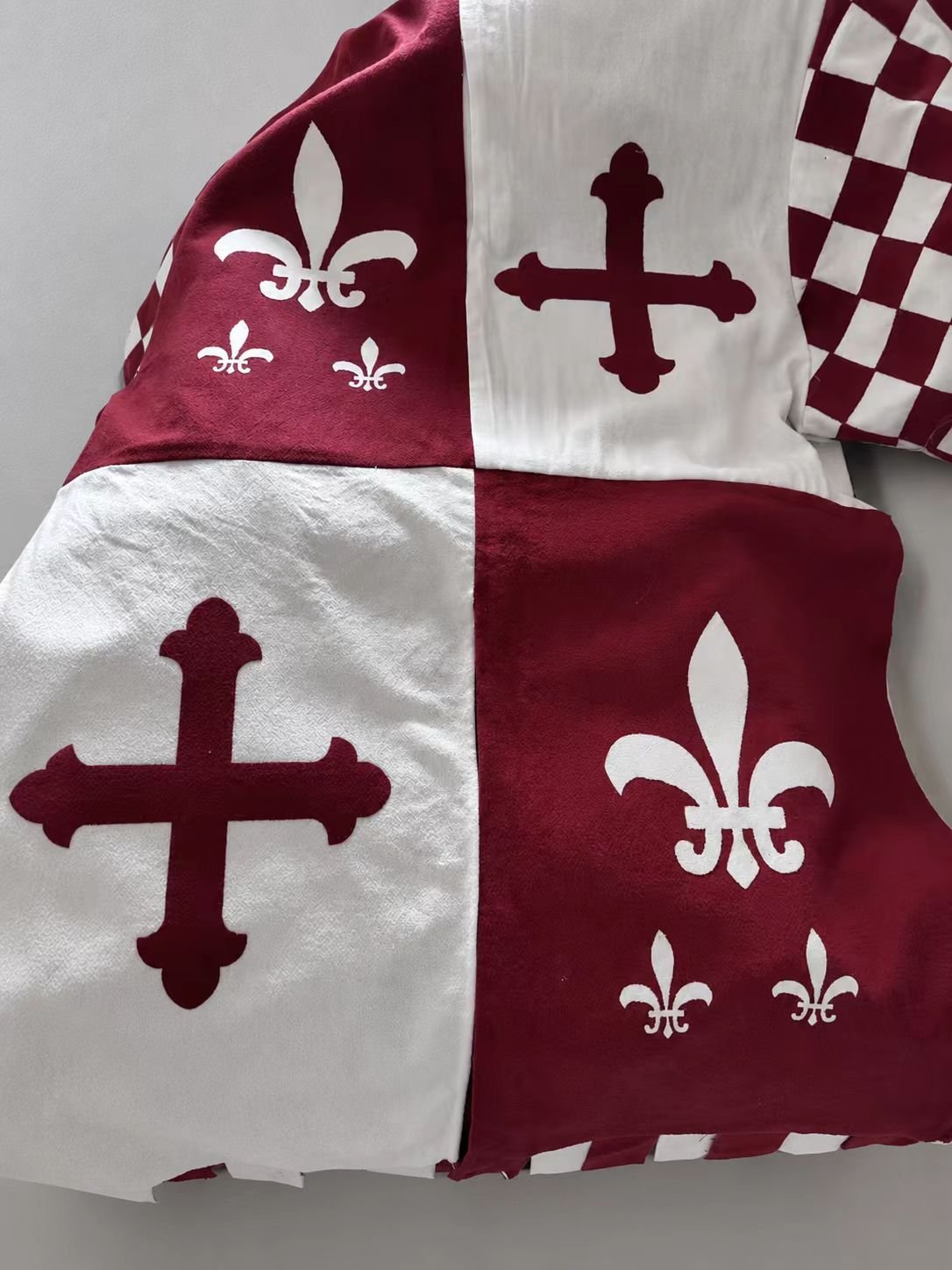 Close-up of burgundy and white medieval cosplay tabard with checker sleeve.