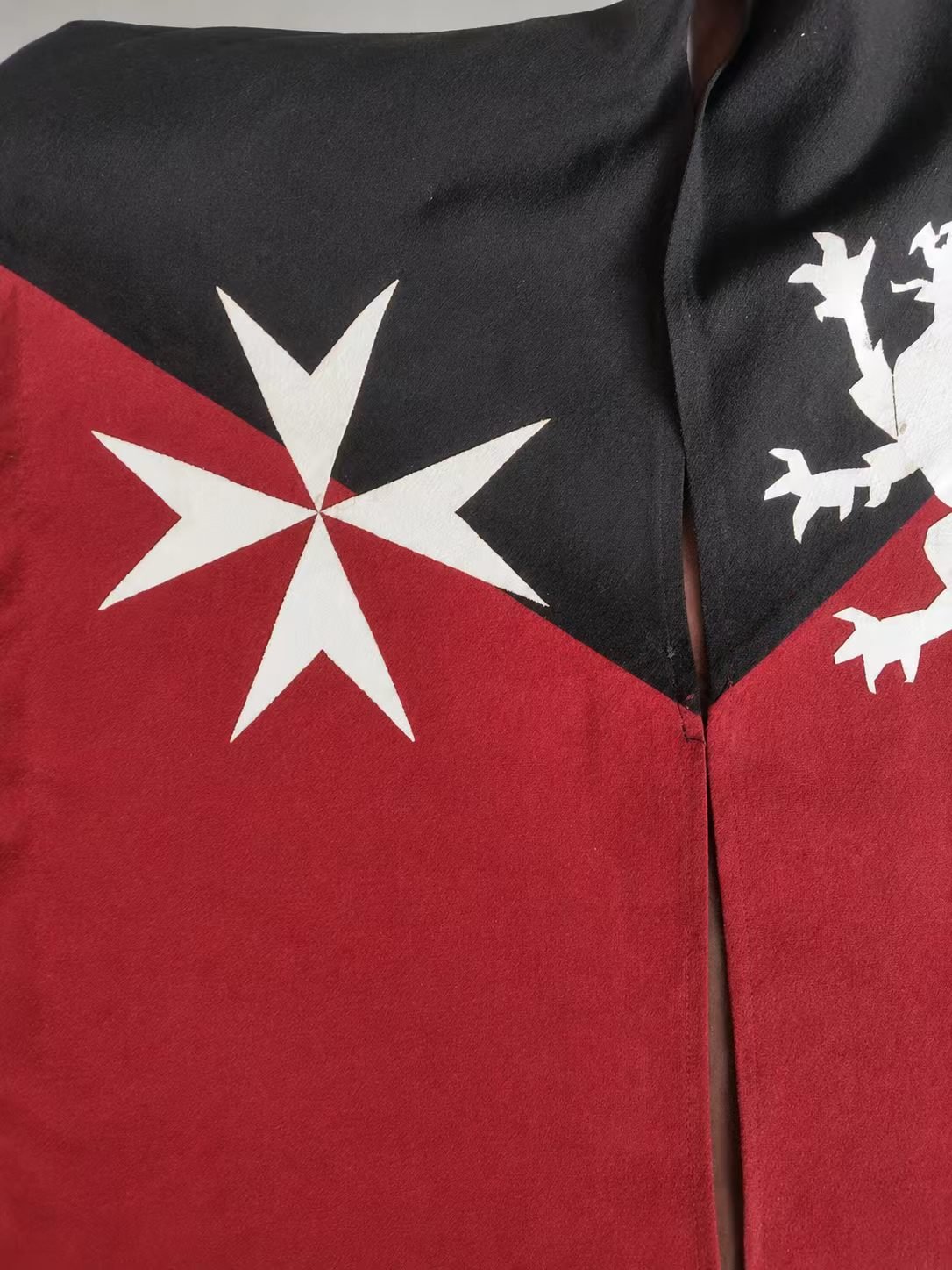 Red and black medieval cosplay textile detail with cross motifs.