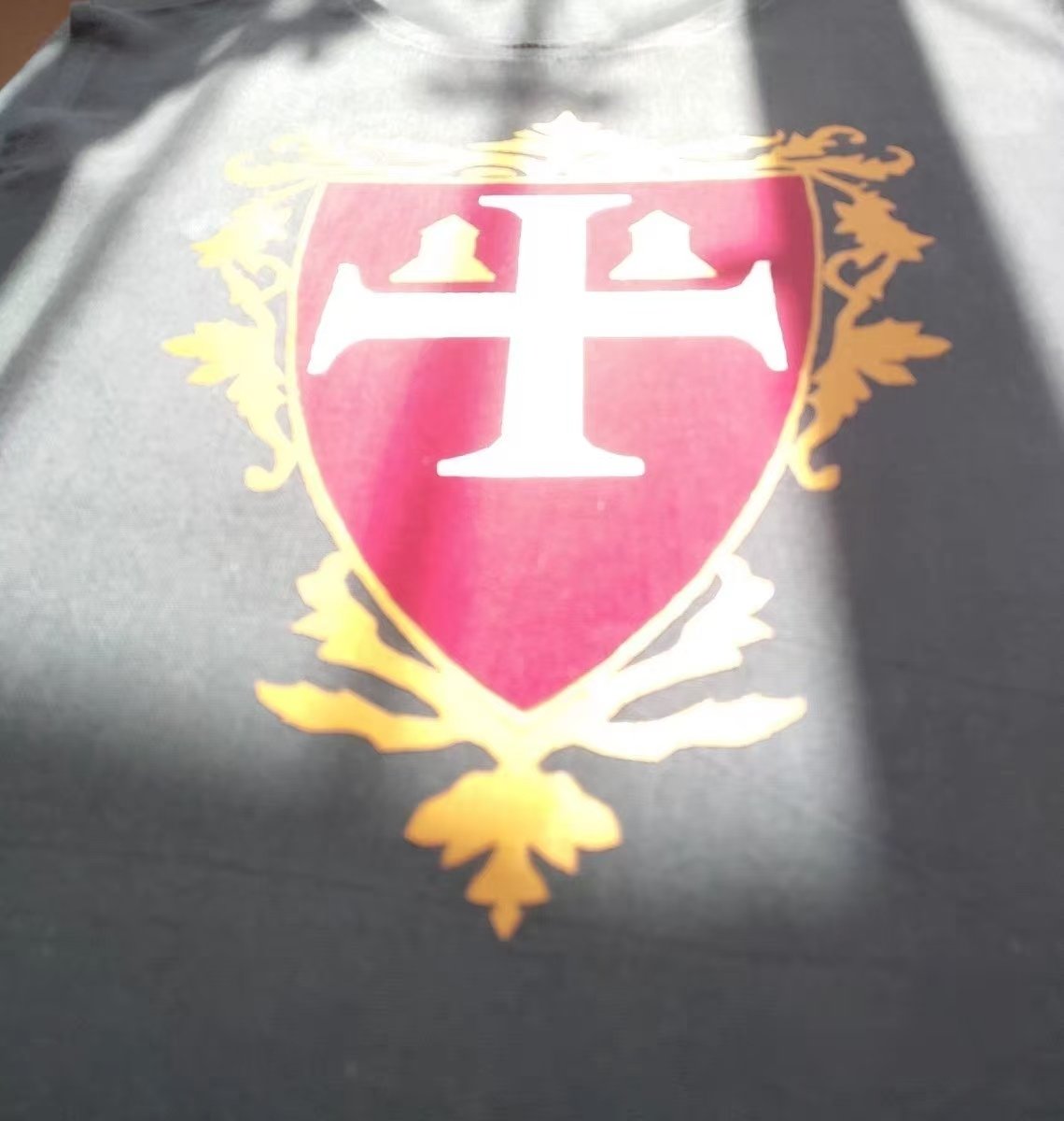 Close-up of a red cross shield crest on dark medieval cosplay fabric.