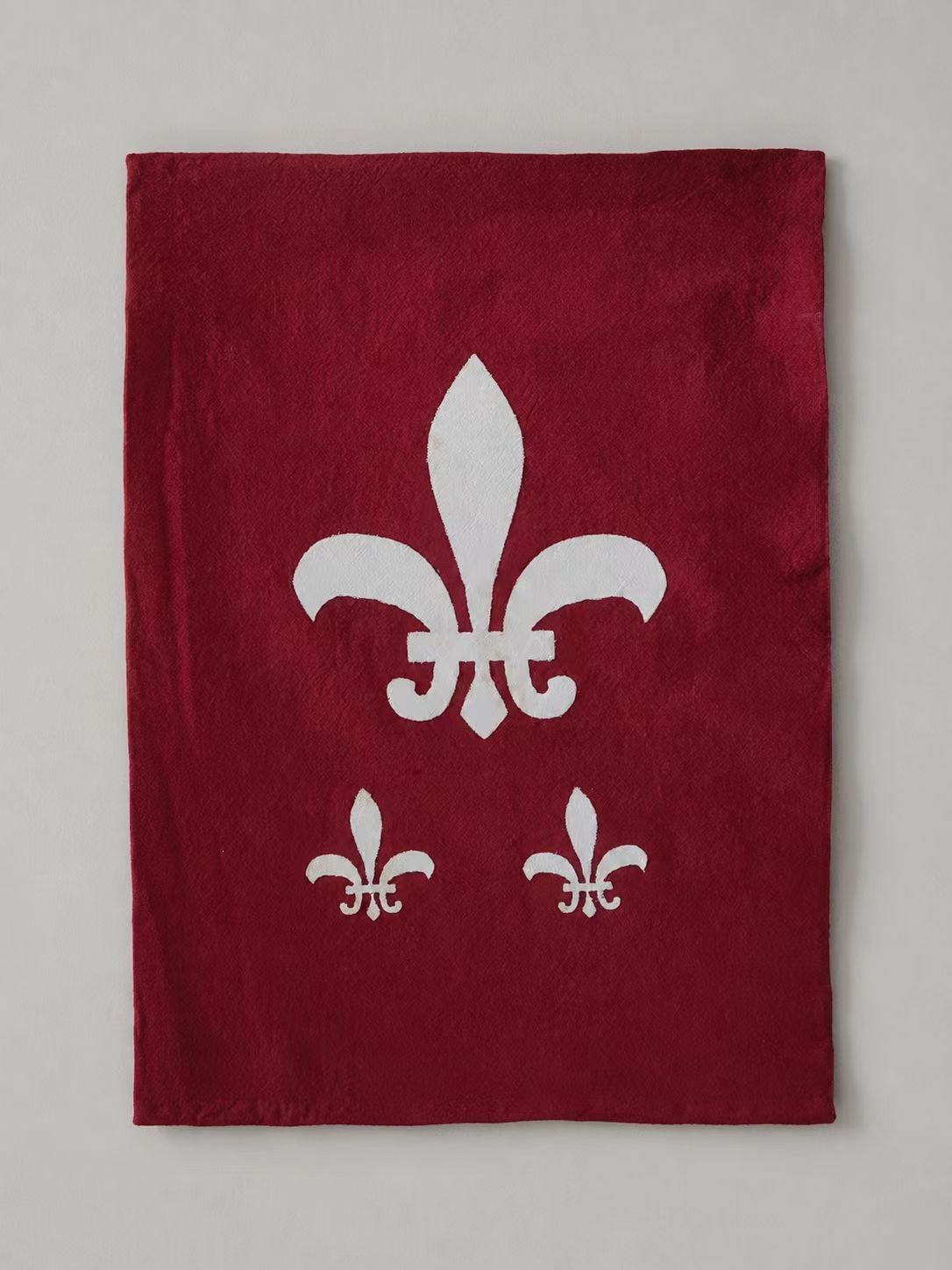 Red medieval cosplay fabric panel with white fleur-de-lis symbols.