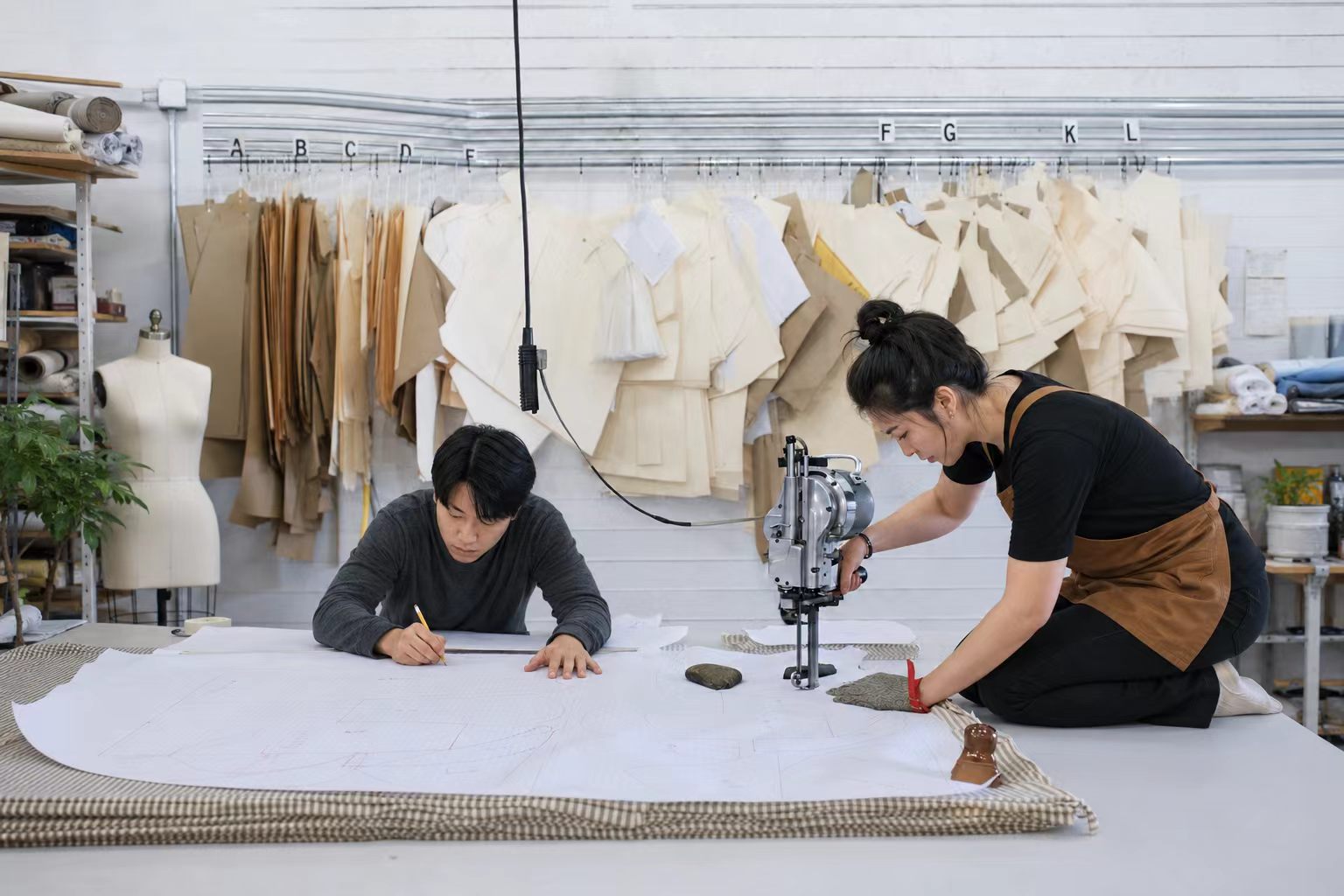 Atelier designer arranging costume reference sketches and fabric notes inside a workshop.