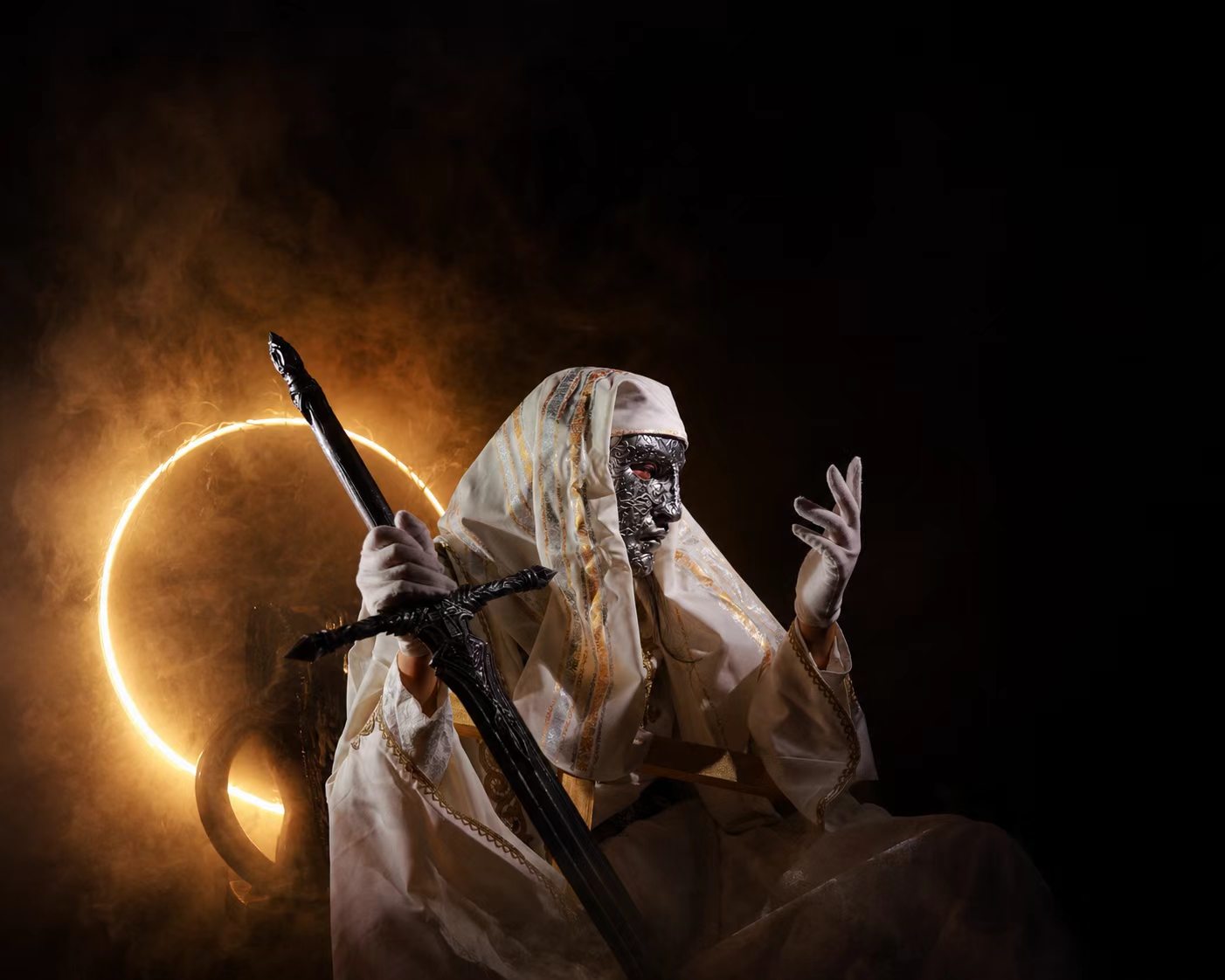 Masked fantasy costume with white robe, black staff, and warm circular backlight.